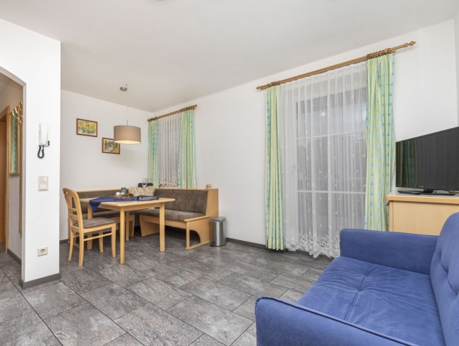 Wohnzimmer mit Essecke und Flat-TV im Appartement 1