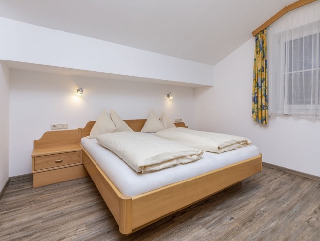 Schlafzimmer mit Doppelbett und Mansarde im Appartement 3